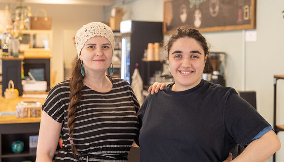 Zwei weibliche FSW-Kundinnen stehen im Verkaufsraum der Tagesstruktur „Das Spezial“ nebeneinander und blicken lächelnd in die Kamera